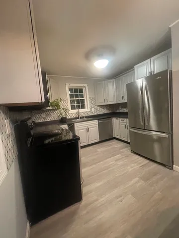 a kitchen with stainless steel appliances granite countertop a refrigerator a stove a sink and a microwave