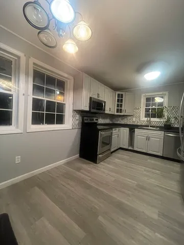 a large kitchen with stainless steel appliances granite countertop a stove and cabinets