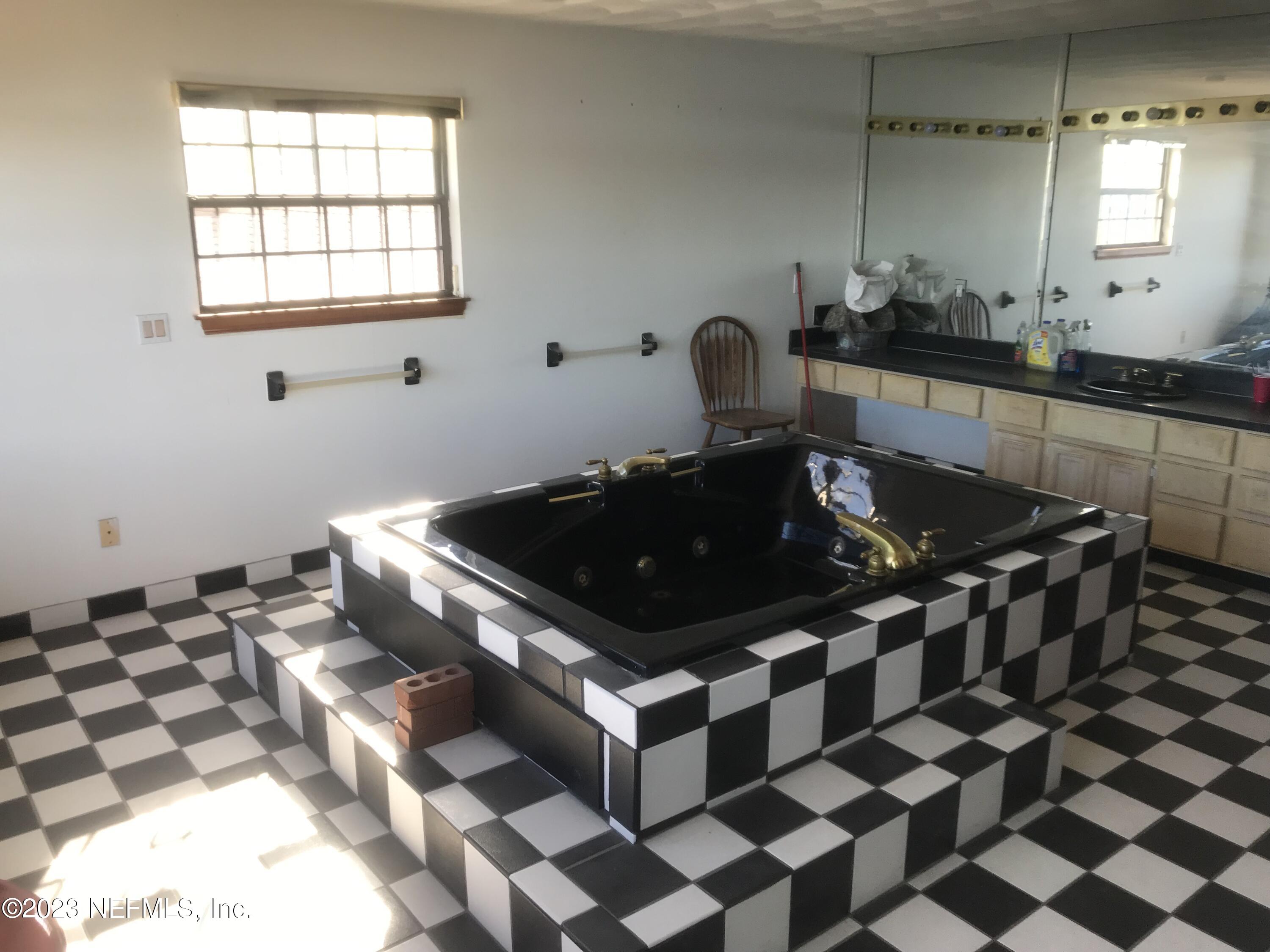 8063 Appian Way Jacksonville, FL 32208 - Photo 20 of 27 a kitchen with a checkered floor and white cabinets