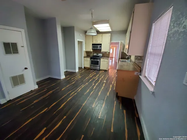 a open kitchen with wooden floor and electronic appliances
