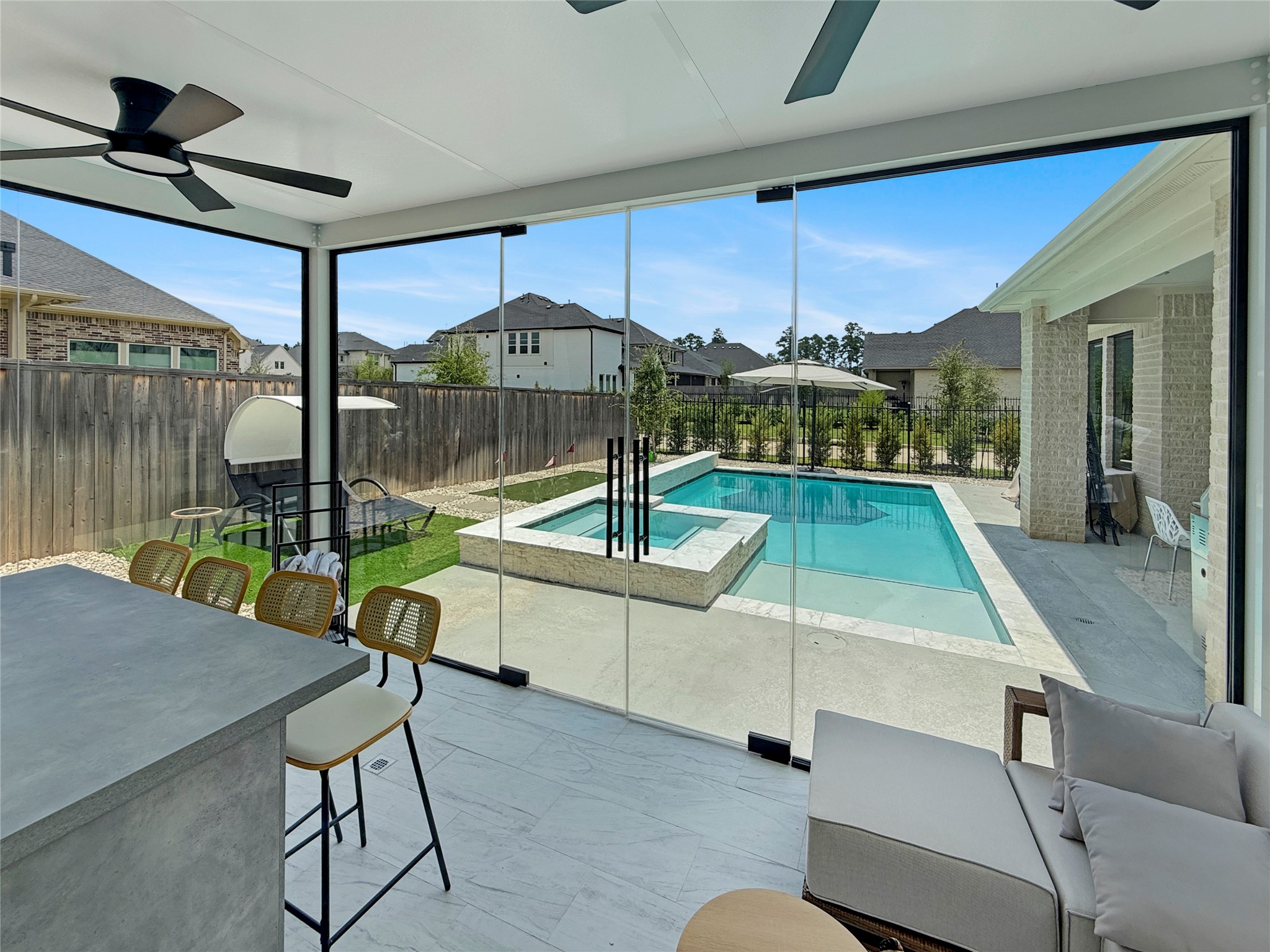 26918 Swanborough Road Spring, TX 77389 - Photo 36 of 50 The outdoor entertaining spaces are warm and welcoming with plenty of spaces for gathering and relaxing — This floor to ceiling glass doors open the covered gazebo completely to the pool, spa, and putting green beyond.