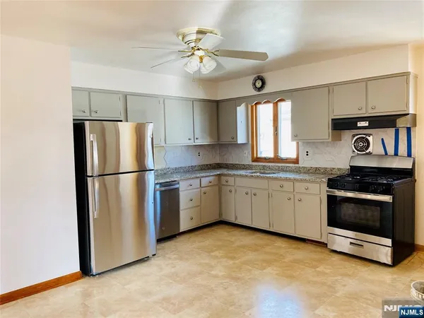 a kitchen with stainless steel appliances granite countertop a refrigerator a sink dishwasher a stove and white cabinets