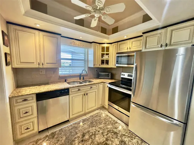 a kitchen with stainless steel appliances granite countertop a refrigerator a stove and a sink