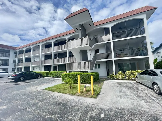 a front view of a building with a garden and parking space