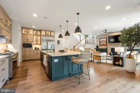 a living room with stainless steel appliances kitchen island granite countertop a table chairs and a view of living room