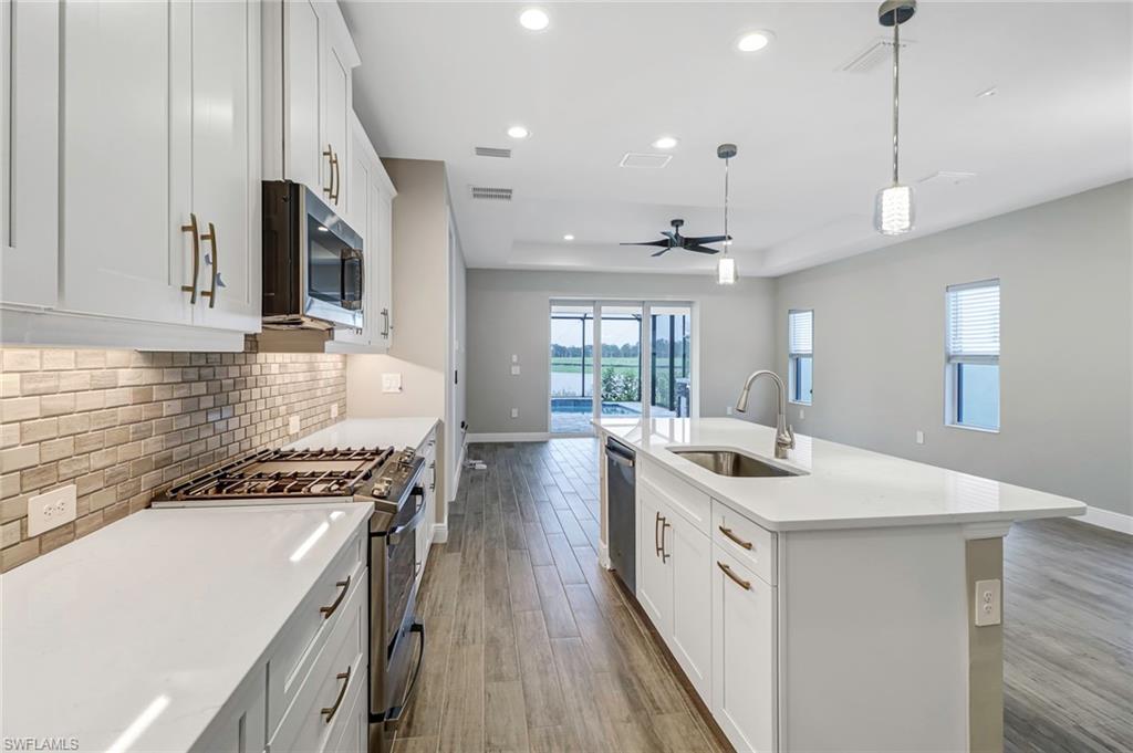 4652 Centaurus Circle Naples, FL 34120 - Photo 4 of 45 Kitchen with stainless steel appliances, white cabinets, dark wood-style floors, a raised ceiling, and ceiling fan