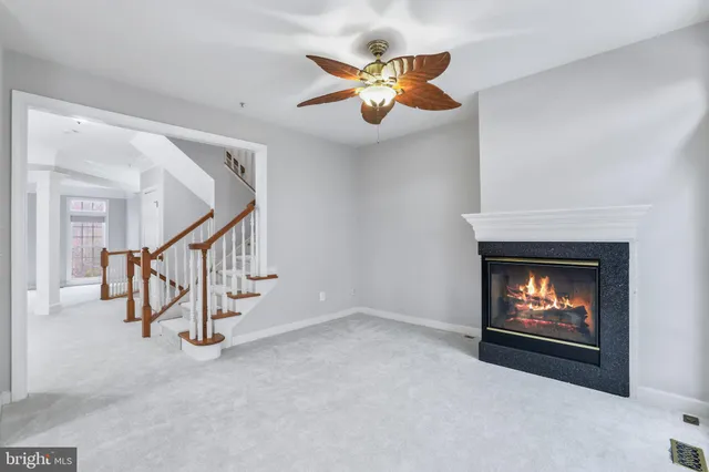a view of an empty room with wooden floor and a ceiling fan