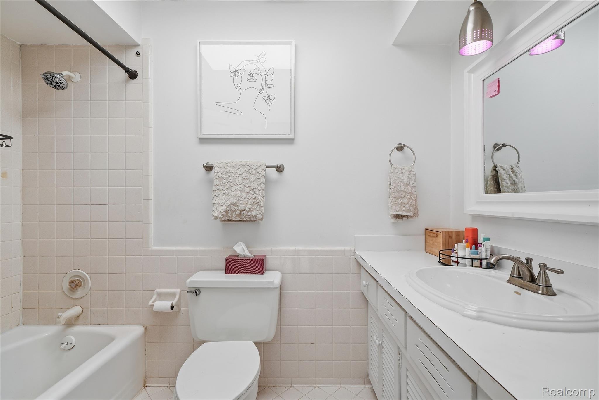 4041 West Maple Road, Unit E203 Bloomfield Hills, MI 48301 - Photo 17 of 25 Bathroom featuring shower / bathtub combination, vanity, tile walls, and a wainscoted wall