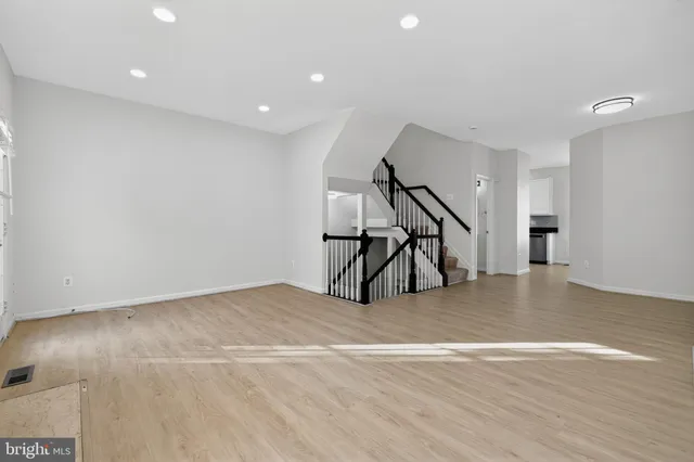 a view of an empty room with stairs and a ceiling fan