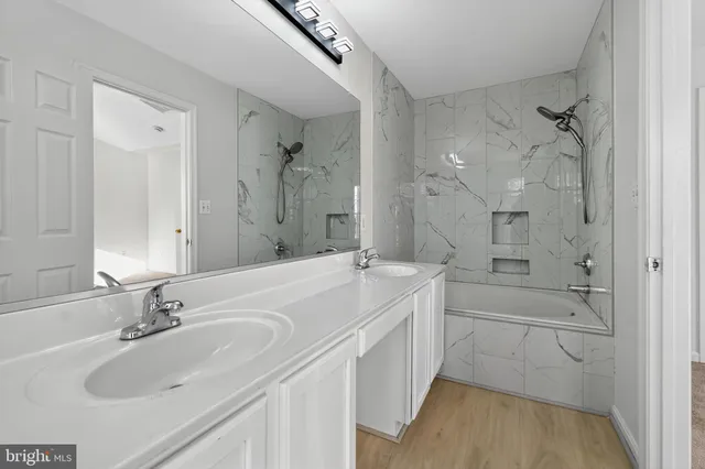 a bathroom with a tub sink double vanity granite and a mirror