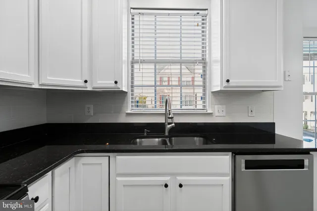 a kitchen with granite countertop white cabinets and black appliances