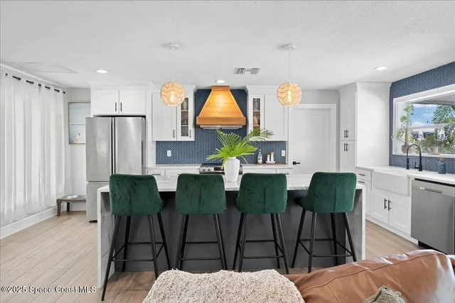 a kitchen with stainless steel appliances granite countertop a stove a sink and white cabinets with wooden floor