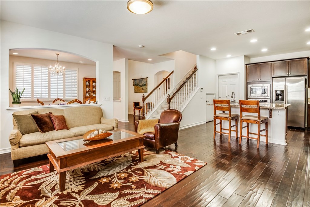 a living room with furniture kitchen view and a wooden floor