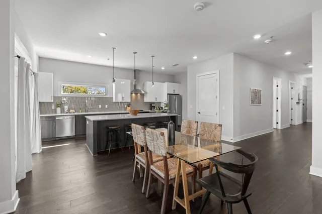a kitchen with stainless steel appliances kitchen island granite countertop a table chairs stove and white cabinets