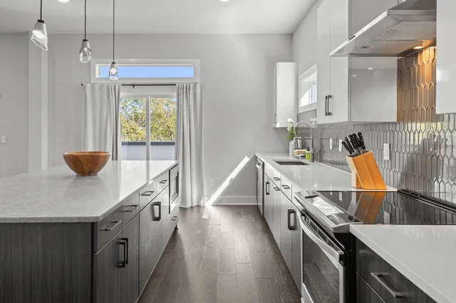 a kitchen with kitchen island granite countertop a sink a counter top space and stainless steel appliances