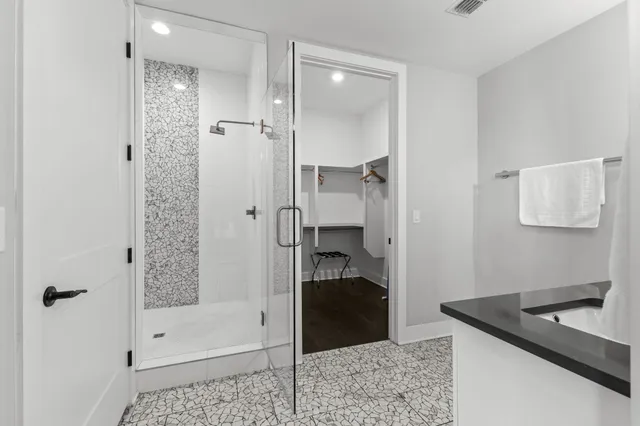 a bathroom with a granite countertop sink a mirror and shower