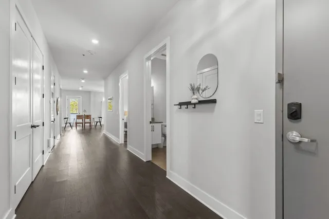 a view of a hallway with wooden floor closet and livingroom