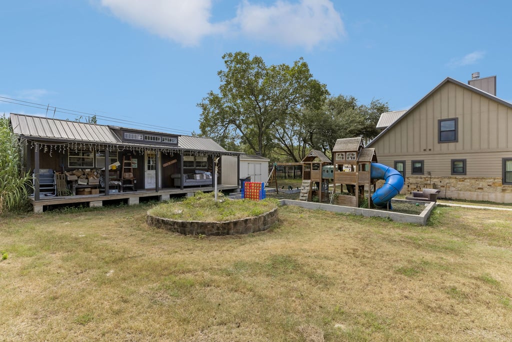 10111 Signal Hill Road Austin, TX 78737 - Photo 30 of 40 An expansive backyard features a detached outbuilding and a wooden play structure under open skies.