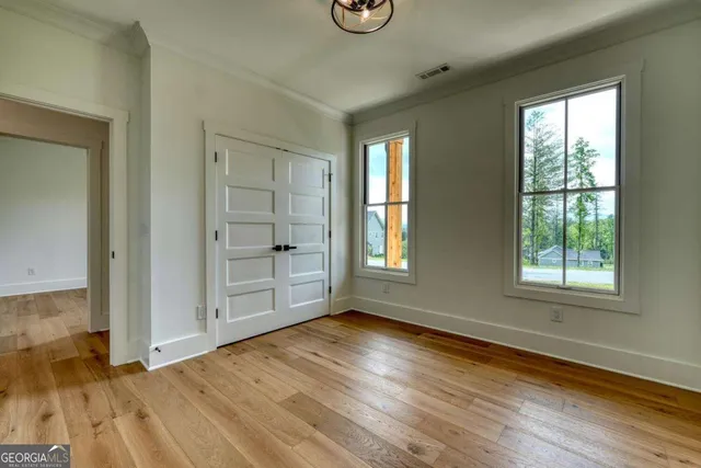 a view of an empty room with wooden floor fireplace and a window