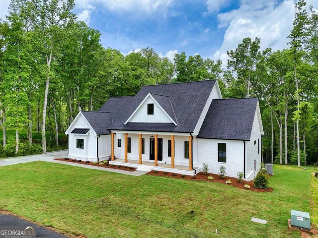 a view of a white house with large windows and a small yard