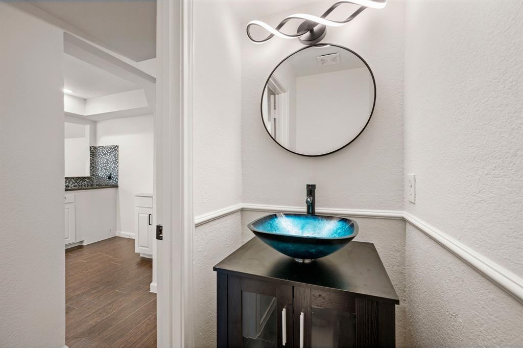 5009 Milam Street Dallas, TX 75206 - Photo 13 of 35 Bathroom with a textured wall, vanity, backsplash, and dark wood-type flooring