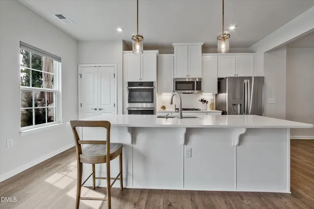 a kitchen with stainless steel appliances a dining table chairs microwave and cabinets