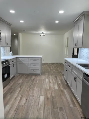 a large kitchen with cabinets wooden floor stainless steel appliances and a sink