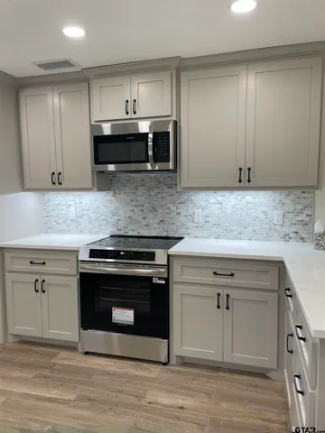 a kitchen with stainless steel appliances granite countertop a stove a sink and a microwave