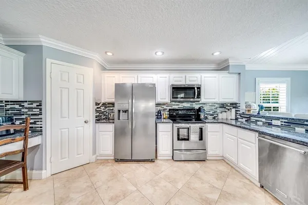 a kitchen with stainless steel appliances granite countertop a refrigerator and a stove top oven