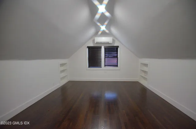 an empty room with wooden floor and fan