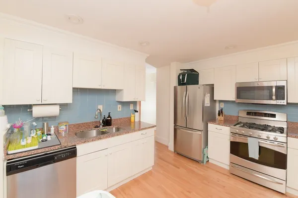 a kitchen with granite countertop a refrigerator stove and microwave