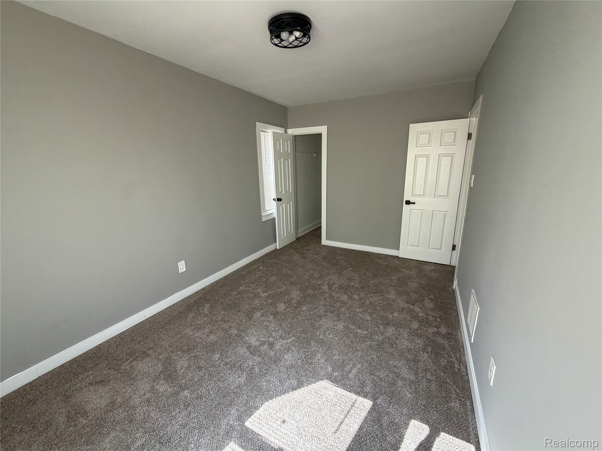 18217 Prairie Street Detroit, MI 48221 - Photo 17 of 34 Spacious room featuring gray walls, gray carpet flooring, white trim, and a black semi-flush mount light fixture