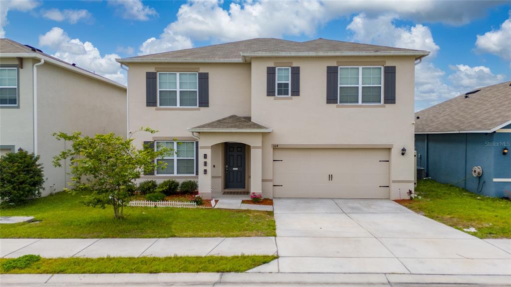a front view of a house with a yard and potted plants