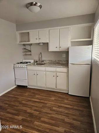 a kitchen with granite countertop a sink a stove a refrigerator and white cabinets