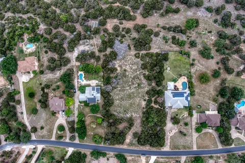 an aerial view of residential house with outdoor space and trees all around