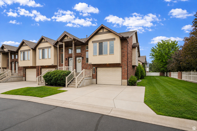 204 Lyman Lane Bountiful, UT 84010 - Photo 1 of 28 Townhome exterior featuring brick and stucco siding, a columned porch entry, and an integrated garage