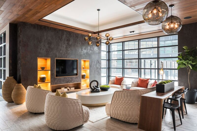 44-28 Purves Street, Unit 19B Queens, NY 11101 - Photo 8 of 19 a living room with furniture a chandelier and a flat screen tv