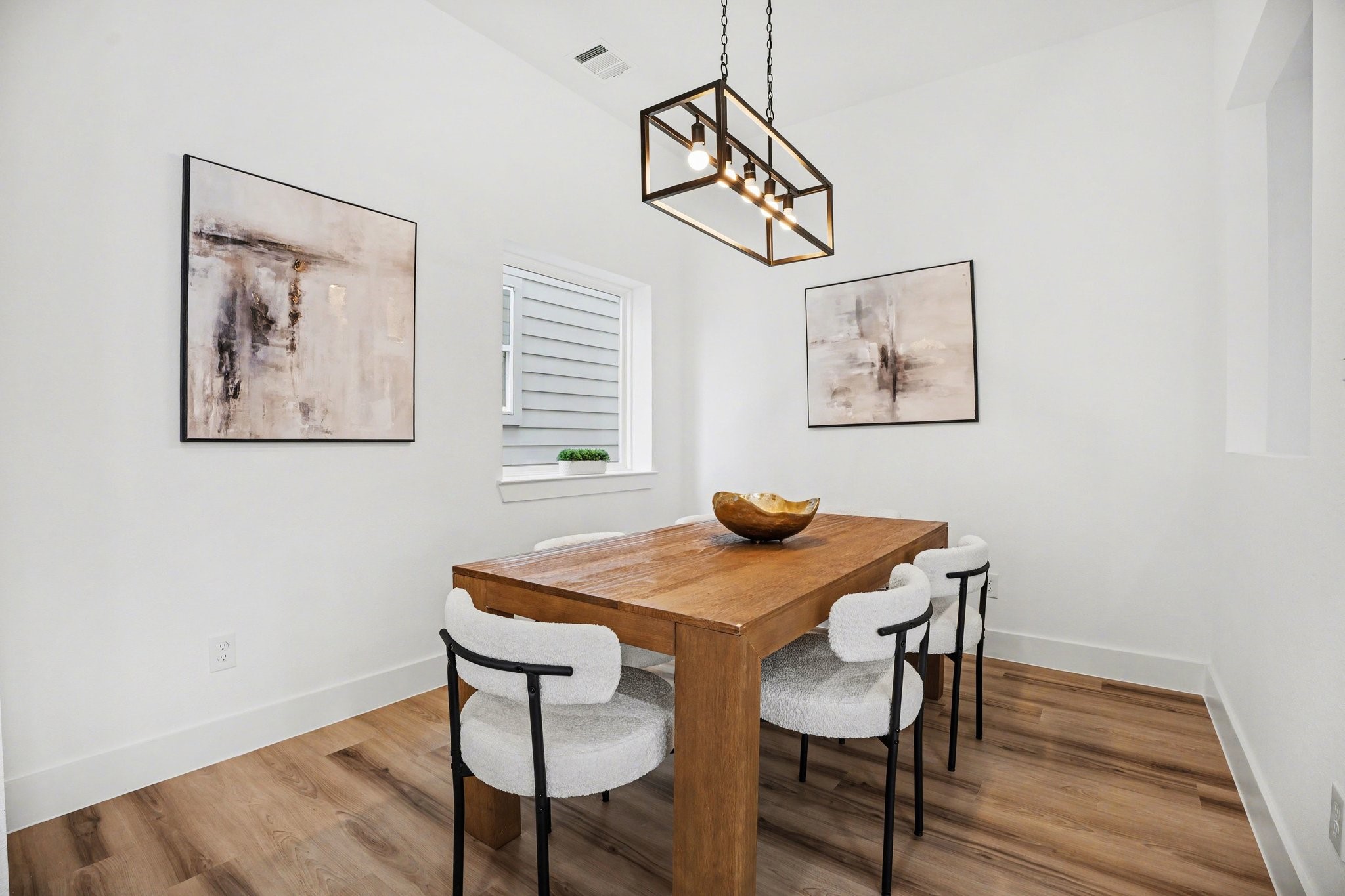 115 Milby Street Houston, TX 77003 - Photo 10 of 28 This dining area features a modern design. It has light wood flooring, white walls, and a stylish rectangular light fixture, creating a bright and inviting space.