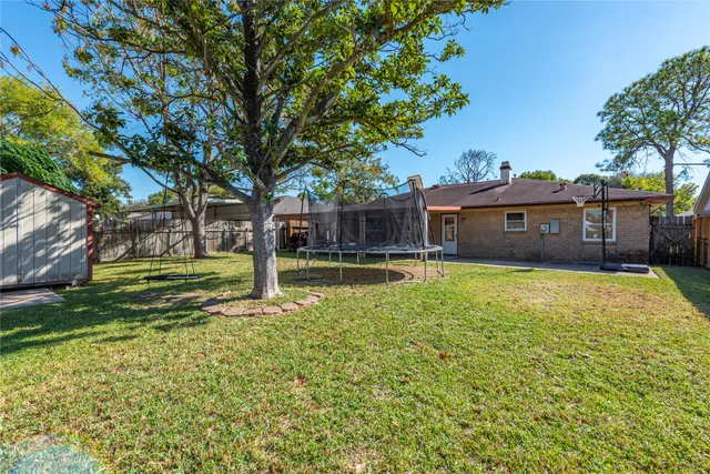 a view of a swimming pool with a yard and palm trees