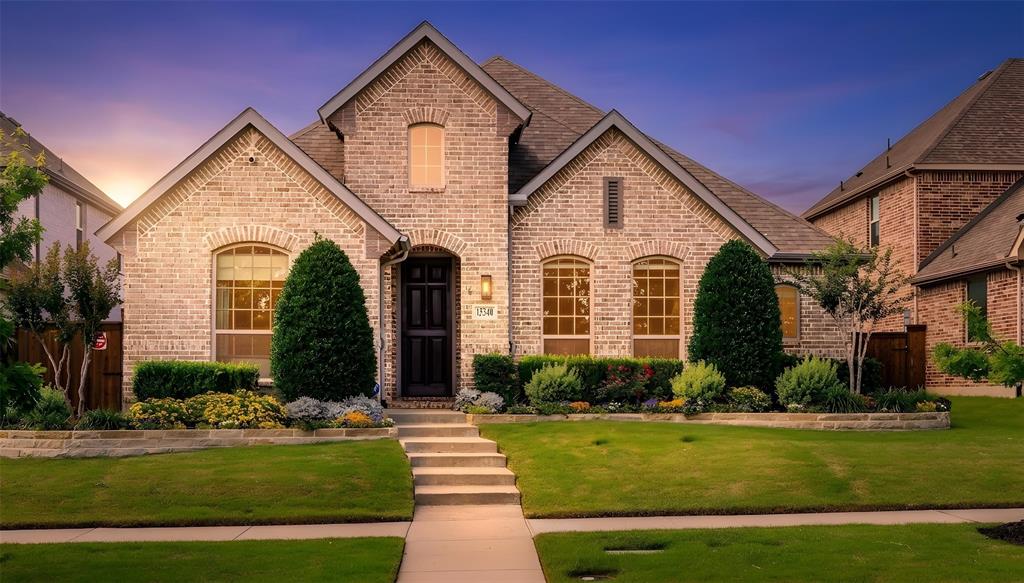 Front exterior featuring light-colored brick with stone accents, a multi-gabled roofline, and a prominent arched entryway
