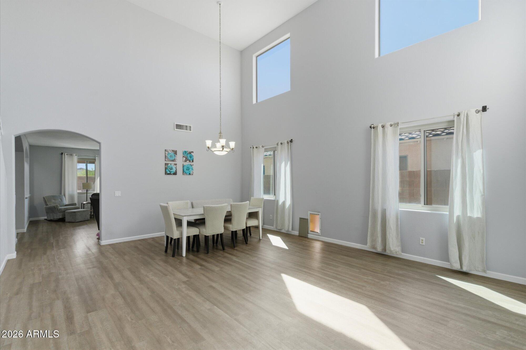 21915 Dietz Drive Maricopa, AZ 85138 - Photo 12 of 31 a dining room with wooden floor a chandelier a glass table and chairs