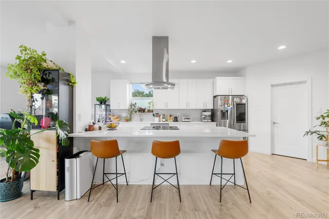 a kitchen with stainless steel appliances kitchen island granite countertop a dining table chairs and white cabinets