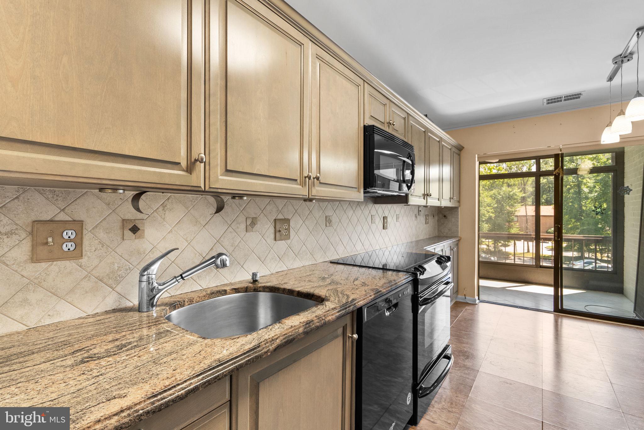6300 Red Cedar Place, Unit 310 Baltimore, MD 21209 - Photo 10 of 28 a kitchen with granite countertop a sink a stove and cabinets