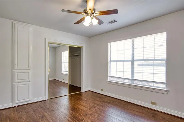 a view of an empty room with window and wooden floor
