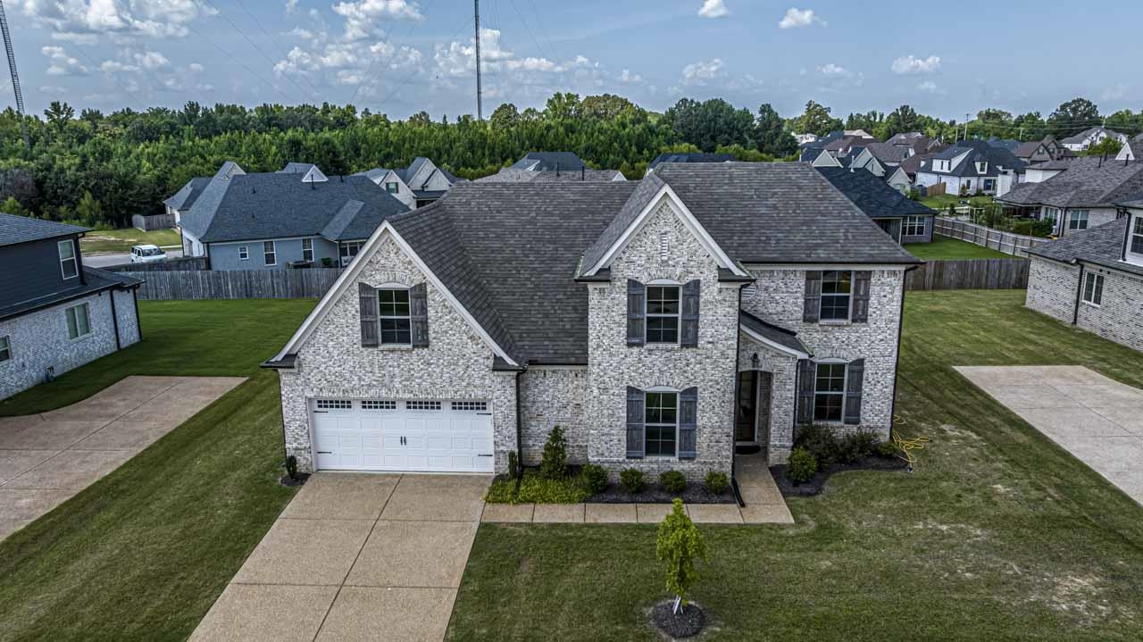 View of front of property featuring concrete driveway, a residential view, stone siding, and an attached garage