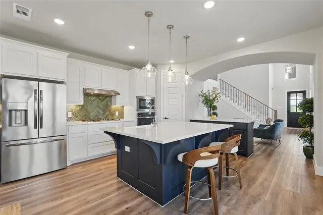 a kitchen with stainless steel appliances a dining table chairs stove refrigerator and wooden floor