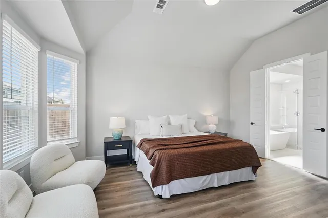 a bedroom with a bed couch and two large window