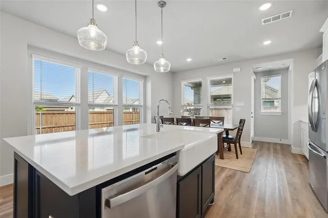 an open kitchen with granite countertop a stove two sinks and wooden floor
