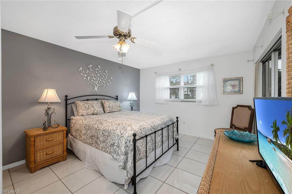 200 Valley Stream Drive, Unit 3B Naples, FL 34113 - Photo 15 of 45 a bedroom with a bed and a chandelier