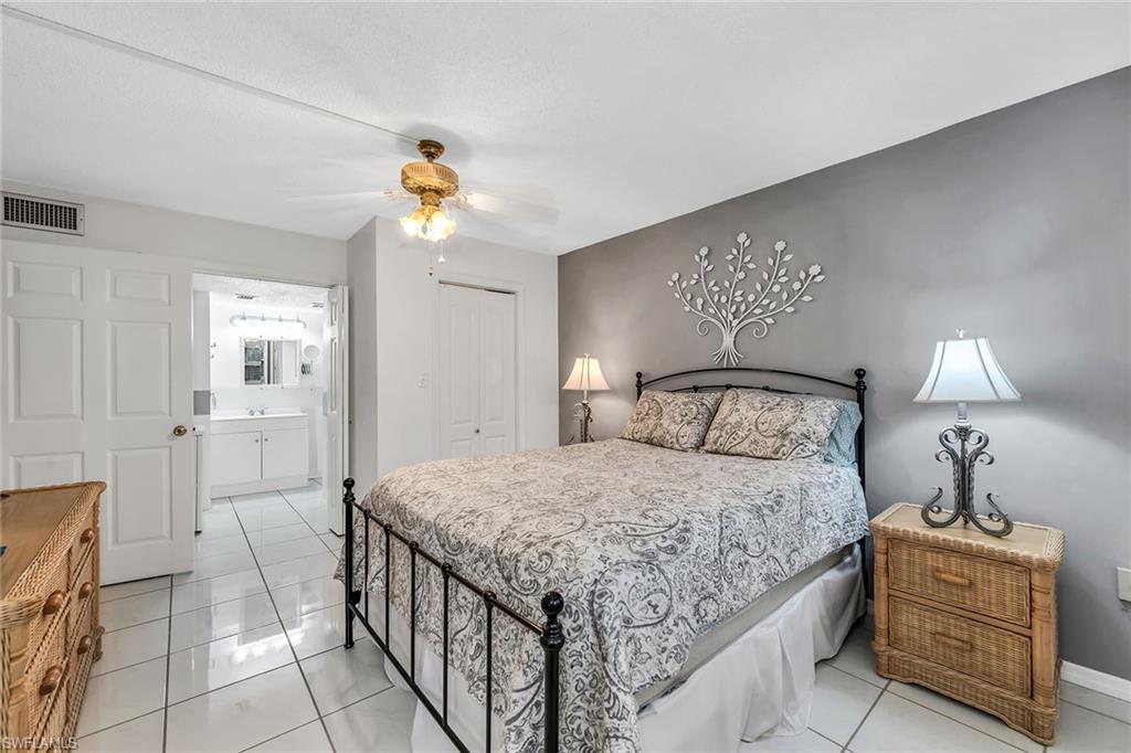 200 Valley Stream Drive, Unit 3B Naples, FL 34113 - Photo 16 of 45 a bedroom with a bed and a chandelier